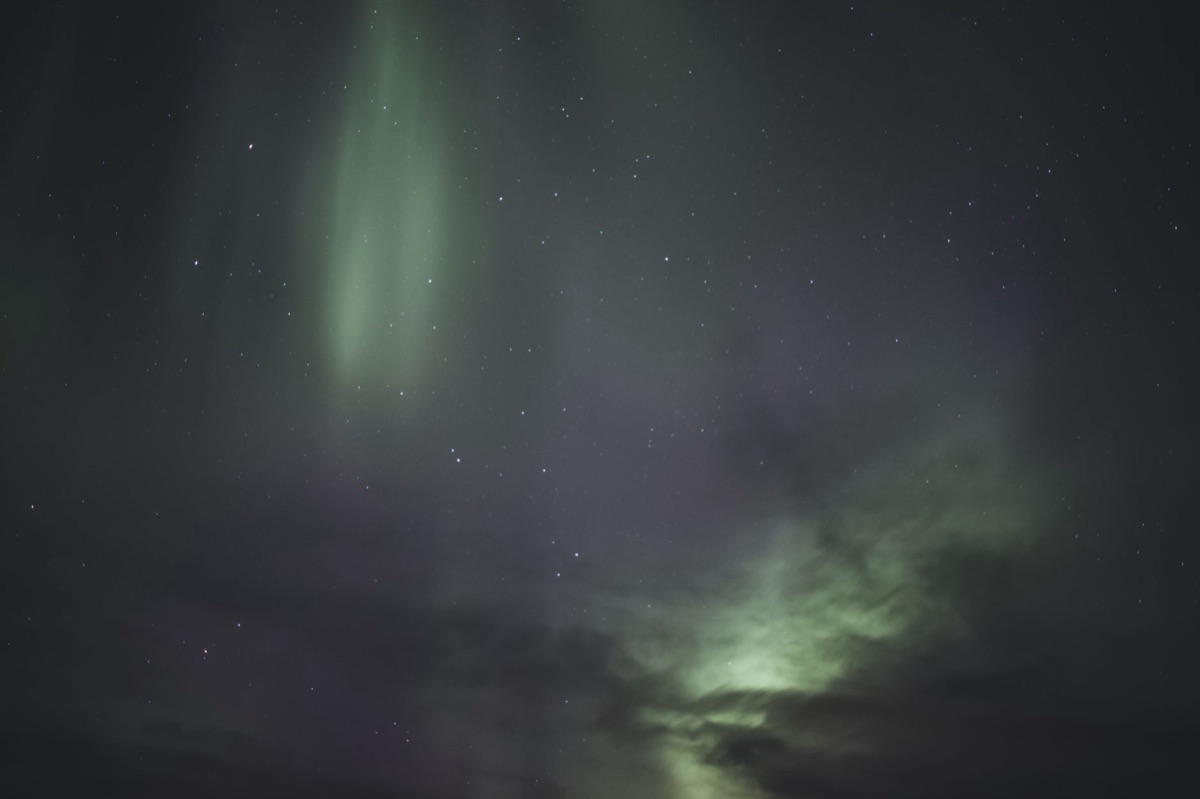 Photorealistic image of a hiking trail in Iceland with a sign pointing to an aurora viewing spot