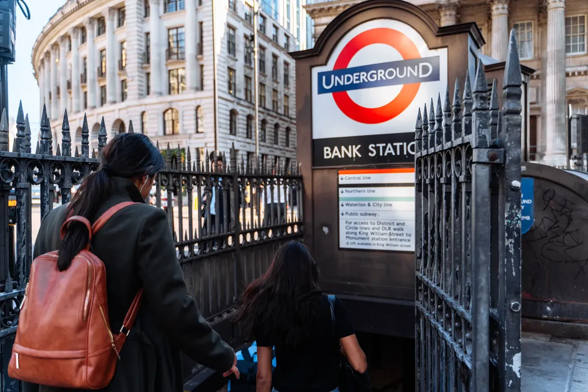 Pedestrians enter the iconic Bank Station in London, highlighting daily urban life.